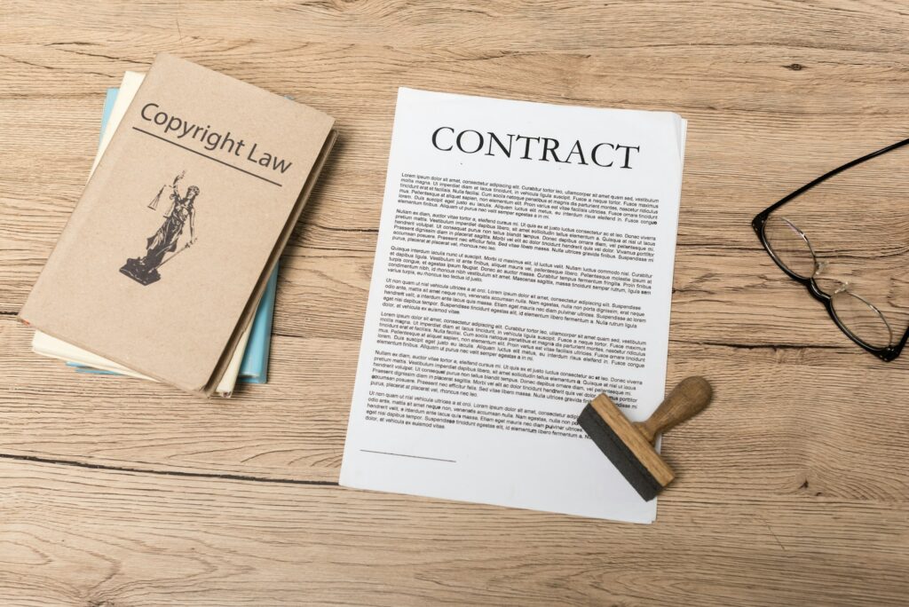 top view of contract, stamp, juridical books and glasses on wooden desk